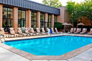a swimming pool with lounge chairs next to a building at Sheraton Milwaukee Brookfield in Brookfield