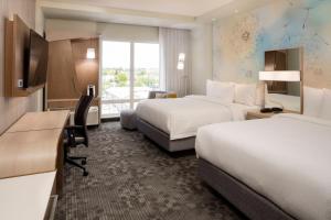 a hotel room with two beds and a television at Courtyard by Marriott Prince George in Prince George