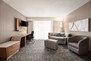 a hotel room with a couch chair and a desk at Courtyard by Marriott Topeka in Topeka