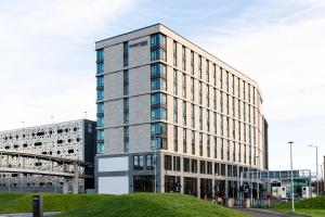 a tall office building with a grassy hill in front of it at Courtyard by Marriott Glasgow SEC in Glasgow