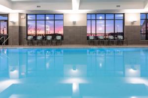 - une piscine avec des tables et des chaises dans un bâtiment dans l'établissement SpringHill Suites Minneapolis Maple Grove/Arbor Lakes, à Maple Grove