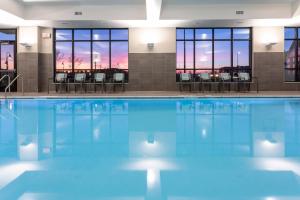 uma piscina com mesas e cadeiras num edifício em SpringHill Suites Minneapolis Maple Grove/Arbor Lakes em Maple Grove