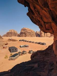 een groep gebouwen in een woestijn met rotsen bij Enad desert camp in Wadi Rum