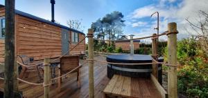 una bañera de hidromasaje en una terraza de madera con una casa de madera en Forton House Shepherd's Huts en Chard