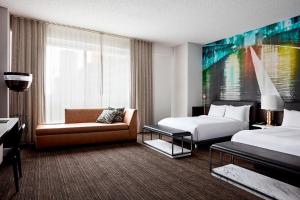 ブルックリンにあるニューヨーク マリオット アット ザ ブルックリン ブリッジのベッド2台とソファが備わるホテルルームです。