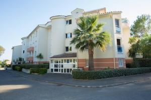 un gran edificio con una palmera delante en Quiet and cozy 1BR close to beach and all services, en Saint-Raphaël