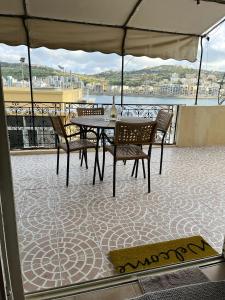 a patio with a table and chairs on a balcony at Groundfloor Apartment By The Sea, Fabulous Views in St Paul's Bay