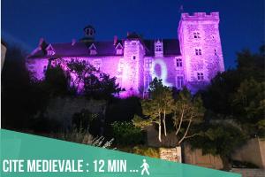 un château éclairé la nuit avec des lumières violettes dans l'établissement Artbleu -Tout Confort - Idéal Pros - Proche commerces, à Montluçon