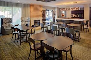 um restaurante com mesas e cadeiras e uma lareira em Courtyard Long Island MacArthur Airport em Ronkonkoma