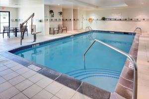 a pool in a hotel with a table and chairs at Courtyard Long Island MacArthur Airport in Ronkonkoma