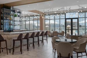 un restaurante con mesas y sillas y un bar en AC Hotel by Marriott Clearwater Beach, en Clearwater Beach