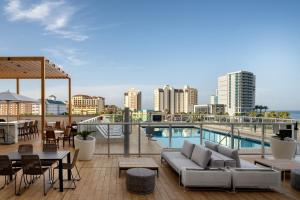 um pátio no último piso com um sofá, mesas e cadeiras em AC Hotel by Marriott Clearwater Beach em Clearwater Beach