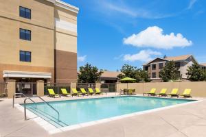 a swimming pool with chairs and a building at SpringHill Suites Fresno in Fresno