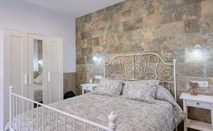 - une chambre avec un lit et un mur en pierre dans l'établissement APARTAMENTO AMARÉ, à Conil de la Frontera