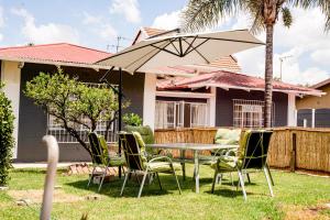 a patio with a table and chairs and an umbrella at Lancaster Guest House in Boksburg