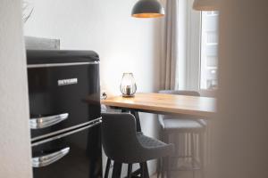 eine Küche mit einem Tisch, einem Kühlschrank und Stühlen in der Unterkunft Koje Sieben I Apartment im Zentrum mit Meerblick in Bremerhaven