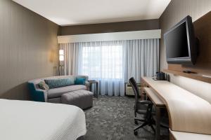 a hotel room with a bed a desk and a tv at Courtyard Kansas City East/Blue Springs in Blue Springs