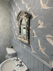 uma casa de banho com um lavatório branco e pássaros na parede em Memory Lane Farmhouse Carlingford em Lubhaidh