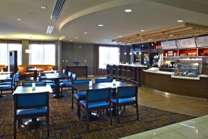 Courtyard by Marriott Hamilton في هاميلتون: مطعم بطاولات وكراسي وبار