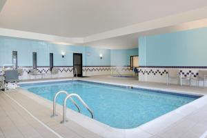 - une grande piscine dans une chambre d'hôtel entourée de chaises dans l'établissement SpringHill Suites by Marriott Newark International Airport, à Newark