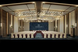 une salle de conférence avec des chaises blanches et un lustre dans l'établissement Sheraton Maoming Hot Spring Resort, à Maoming 30 autres photos