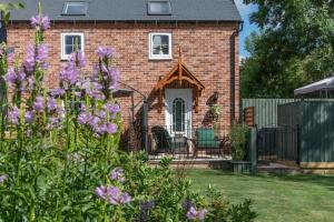 una casa de ladrillo con flores púrpuras en el patio en Luxury retreat in Lincolnshire with hot tub en Cranwell