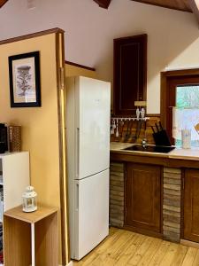 La cuisine est équipée d'un réfrigérateur blanc et d'un évier. dans l'établissement Gîte L'Orée, 