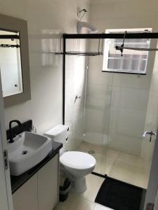 a bathroom with a toilet and a sink and a shower at Apartamento próximo ao Beto Carrero. in Penha