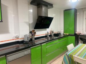 cocina con armarios verdes y TV de pantalla plana en Chalet con piscina, en Simancas