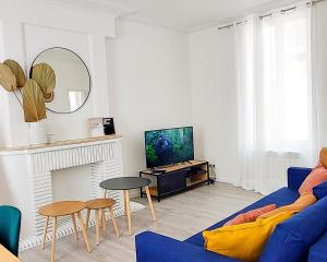 un salon avec un canapé bleu et une télévision dans l'établissement ArtSmalt *Idéal Pro * Proche commerces * 2 chambres * Tout confort, à Montluçon