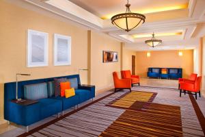 a living room with a blue couch and orange chairs at Courtyard by Marriott Covington / Mandeville in Covington