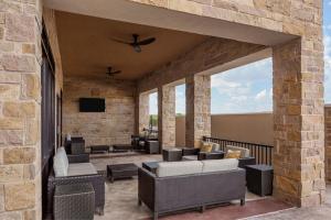 eine Terrasse mit Sofas und einem TV an einer Backsteinwand in der Unterkunft Courtyard by Marriott San Angelo in San Angelo