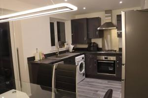una cucina con armadi neri, lavatrice e lavandino di 3 Bedroom Full Property a Cramlington