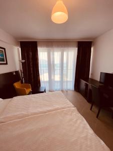 Schlafzimmer mit einem Bett, einem Schreibtisch und einem Fenster in der Unterkunft Hotel Vienna in Herceg-Novi