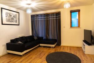 a living room with a black couch and a tv at Lovely 1-Bed Apartment in Hackney London in London