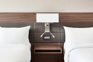 a bedroom with two beds and a night stand with a light at AC Hotel by Marriott Columbus Downtown in Columbus