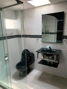 a bathroom with a black toilet and a sink at Casa Merce in Pereira