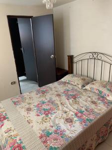 a bedroom with a bed with a floral quilt on it at Casa Merce in Pereira