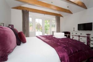 a bedroom with a large white bed with purple sheets at Wolviston Cottage in Wolviston