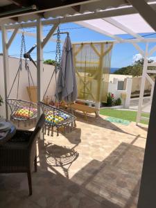 eine Terrasse mit Stühlen, einem Sonnenschirm und einer Schaukel in der Unterkunft Chez Laurenn in Le Carbet
