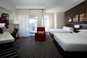 Delta Hotels by Marriott Montreal في مونتريال: غرفة فندقية بسريرين وكرسي احمر