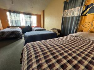 a hotel room with two beds and two windows at Hostal Pachamama Lodge in Cuenca