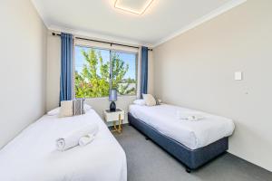 2 camas en una habitación con ventana en Swan Valley Serviced Apartments, en Middle Swan