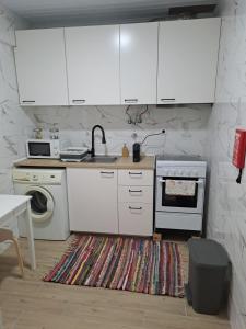 een keuken met witte kasten, een wastafel en een vaatwasser bij Tree House II in Setúbal