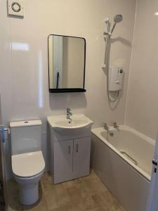 a bathroom with a toilet and a sink and a bath tub at Spacious one bedroom flat, entire property. in Greenock