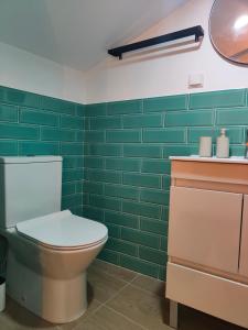 a bathroom with a toilet and green tiles at Wood Essence Apartment - Cozy Balcony in Coimbra