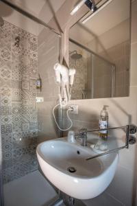 ein Bad mit einem Waschbecken, einer Dusche und einem Spiegel in der Unterkunft Hotel La Tavola Rotonda in Assisi