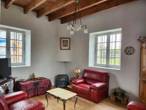 a living room with red leather chairs and a table at Maison chaleureuse et familiale. in Nalliers