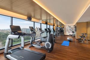 a gym with cardio equipment in a building with windows at Fairfield by Marriott Mumbai International Airport in Mumbai