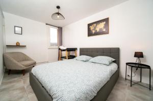 - une chambre avec un lit et une chaise dans l'établissement Appartement climatisé terrasse parking 8 couchages, à Marseille